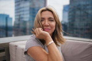 A woman sitting on top of a couch in front of a window.