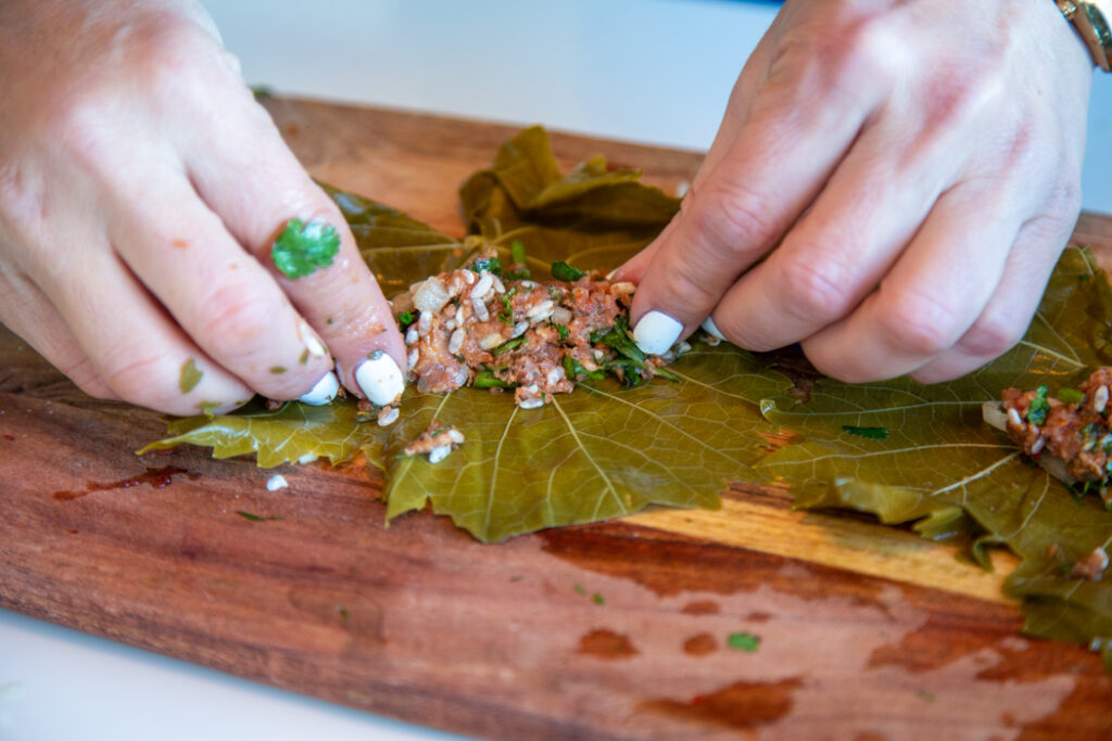 A person is cutting some food on a wooden board