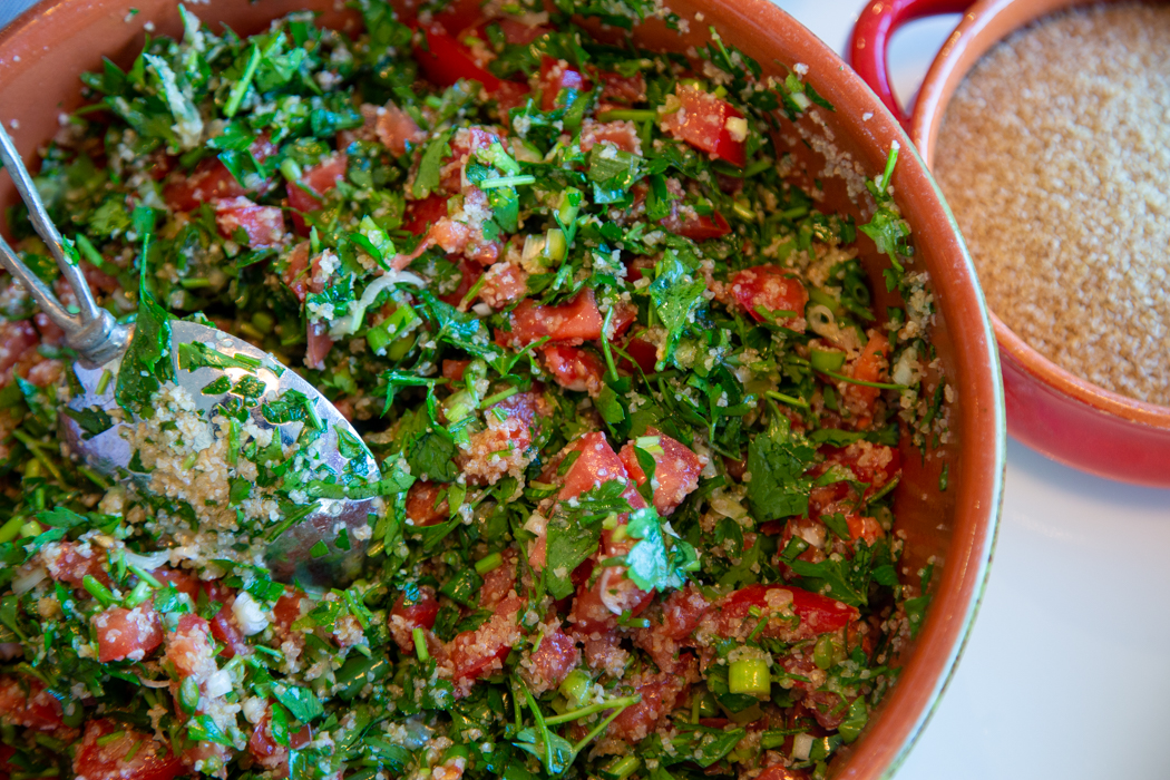 A bowl of food with tomatoes and greens.