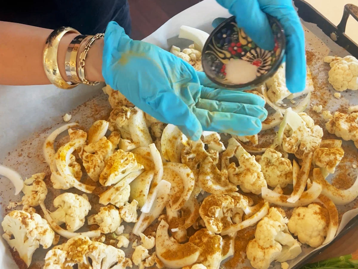 A person wearing blue gloves holding a bowl of food.