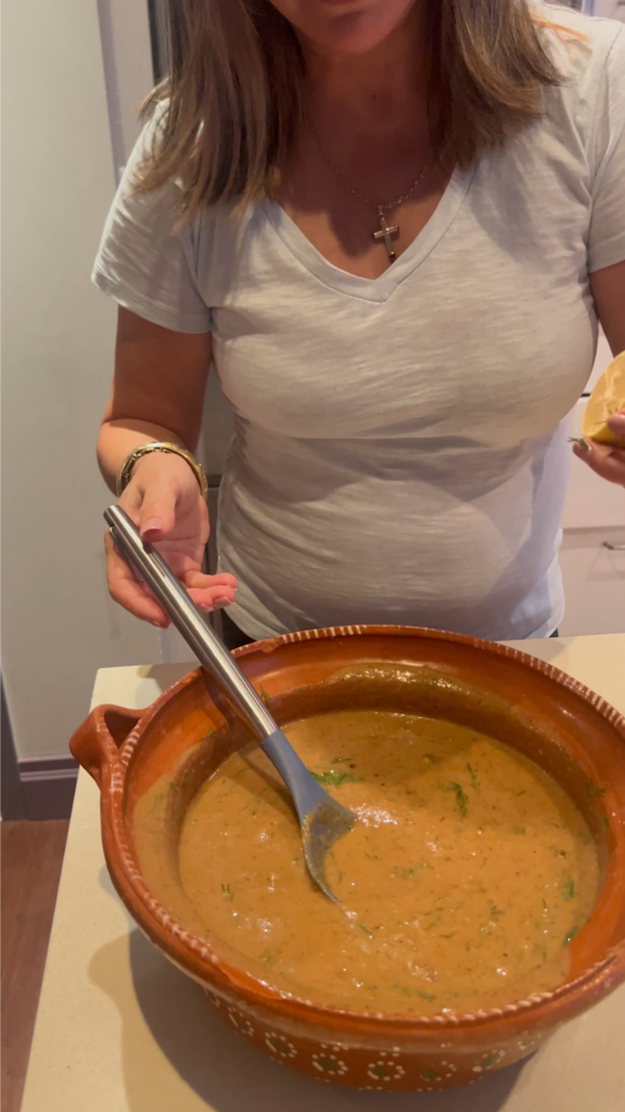 A woman is stirring soup in a large pot.