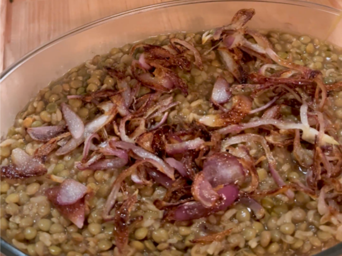 A bowl of lentils and onions on top of the table.