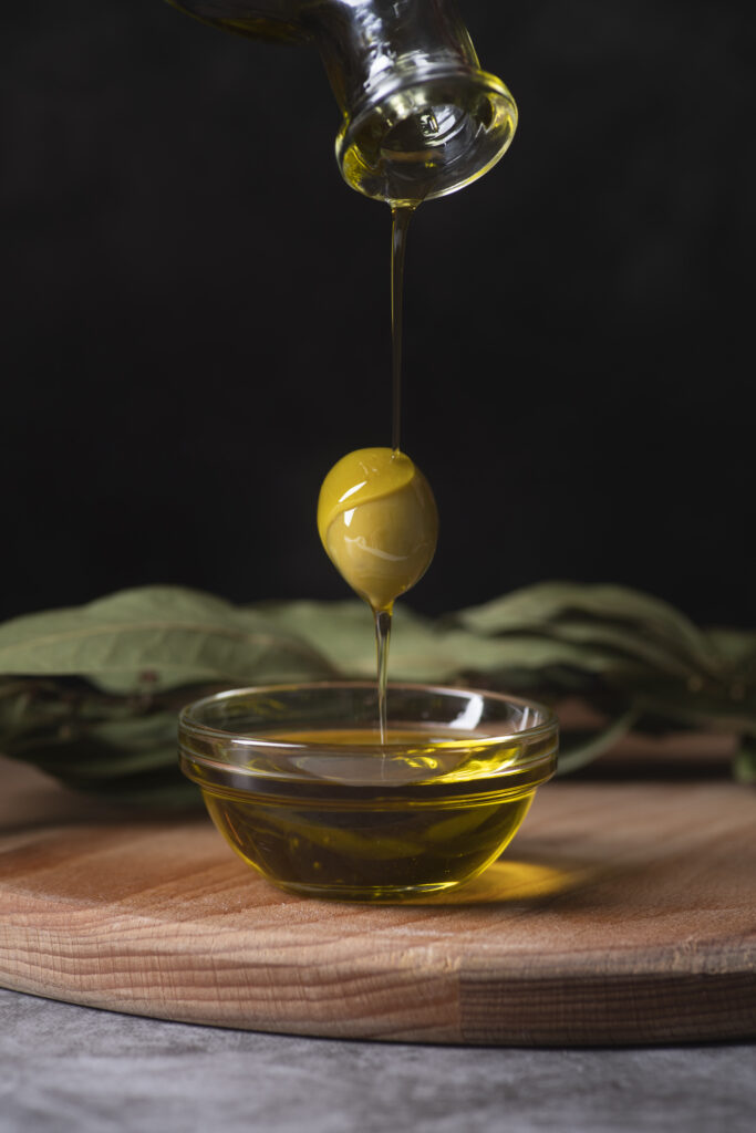 A spoon is being lifted from an olive oil bowl.