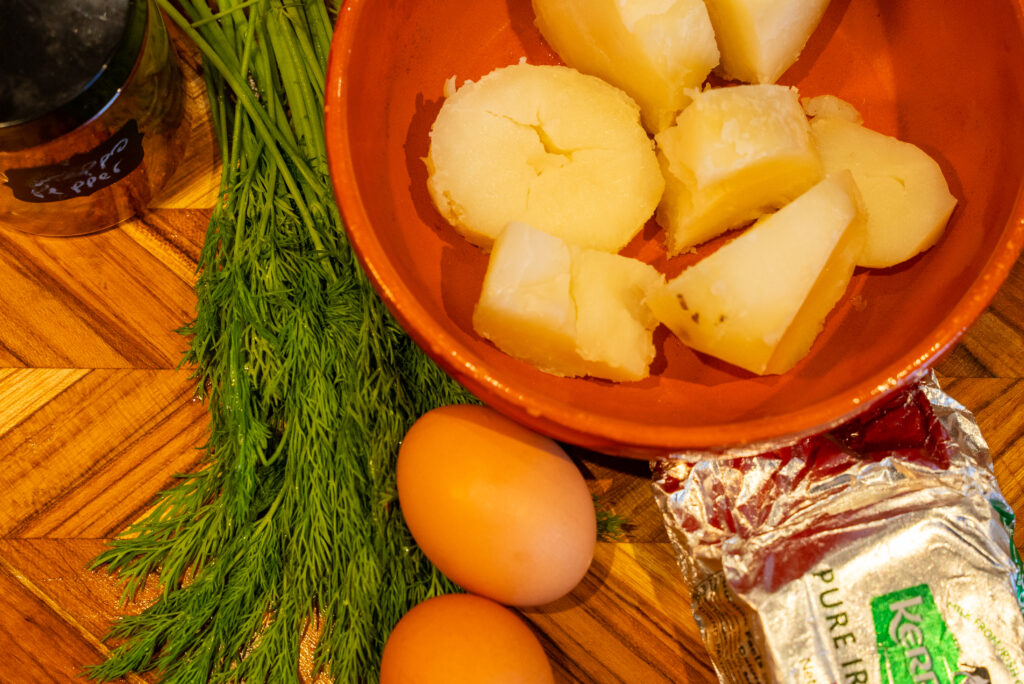 A bowl of fruit next to some eggs and a bag.