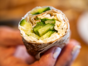 A person holding a burrito with some vegetables