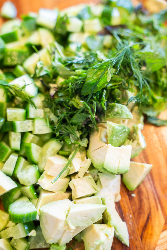 A table topped with avocados, cucumbers and other vegetables.