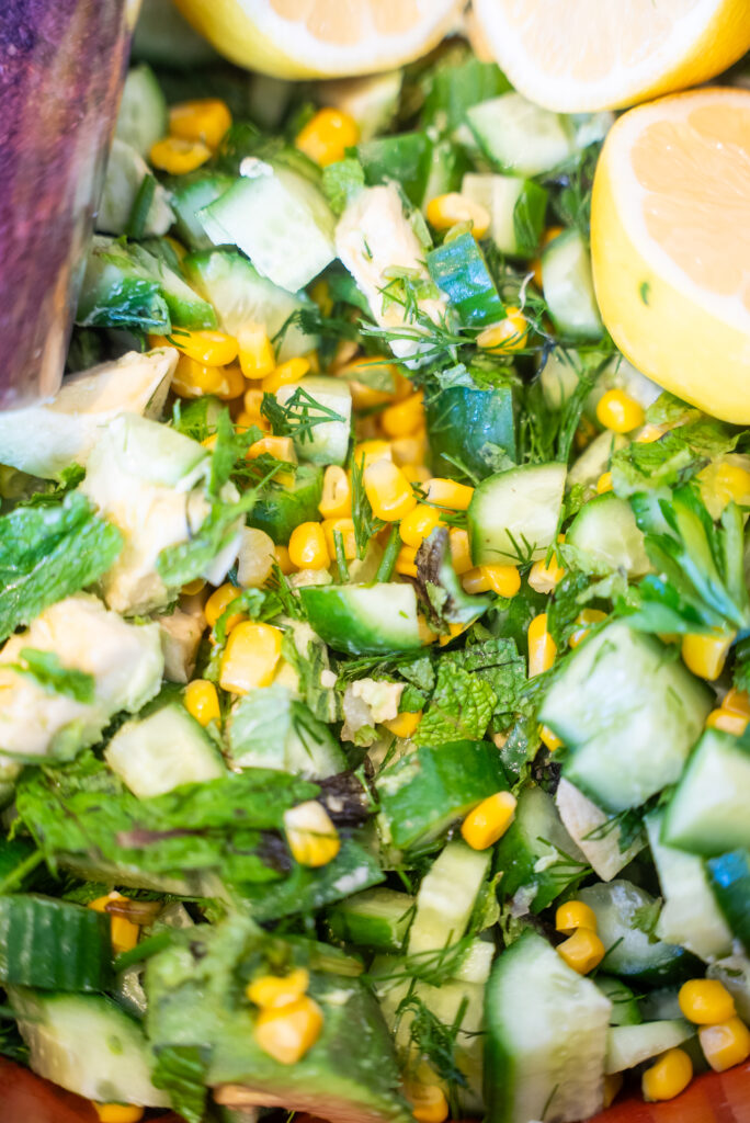 A table topped with avocados, cucumbers and other vegetables.