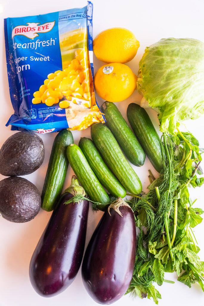 A table topped with avocados, cucumbers and other vegetables.