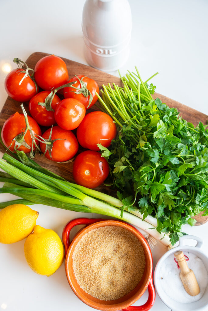 A cutting board with tomatoes, celery and herbs.