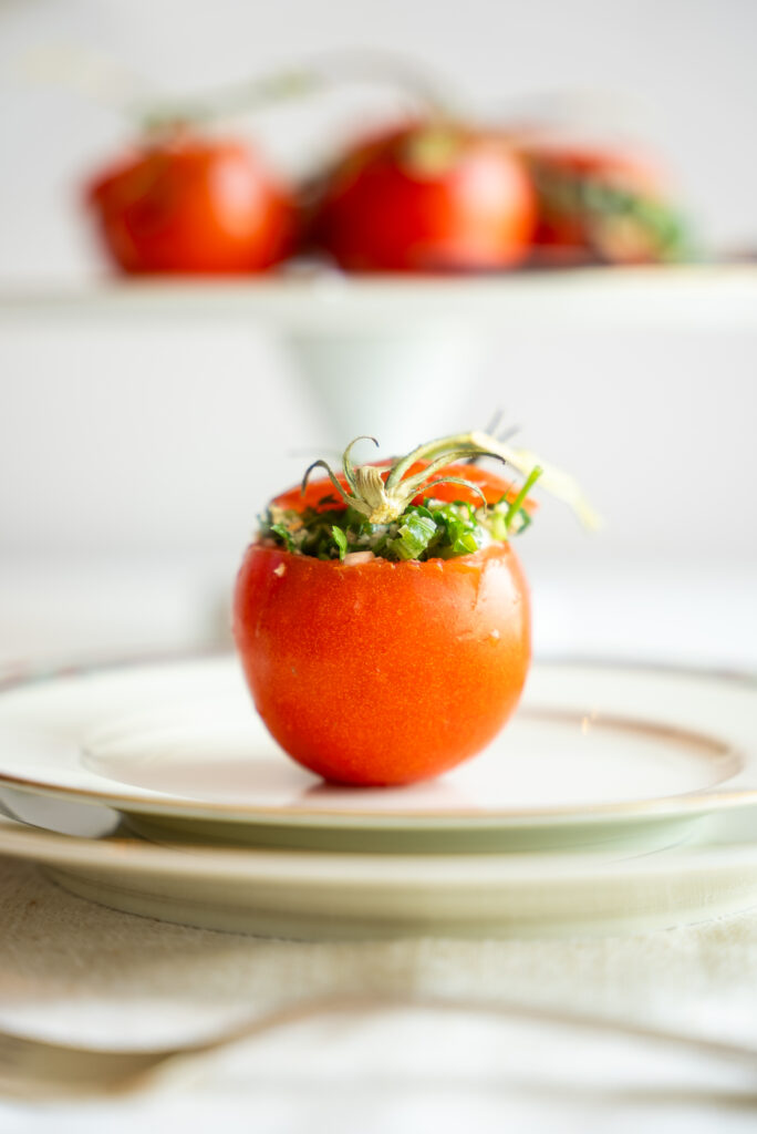 A cutting board with tomatoes, celery and herbs.