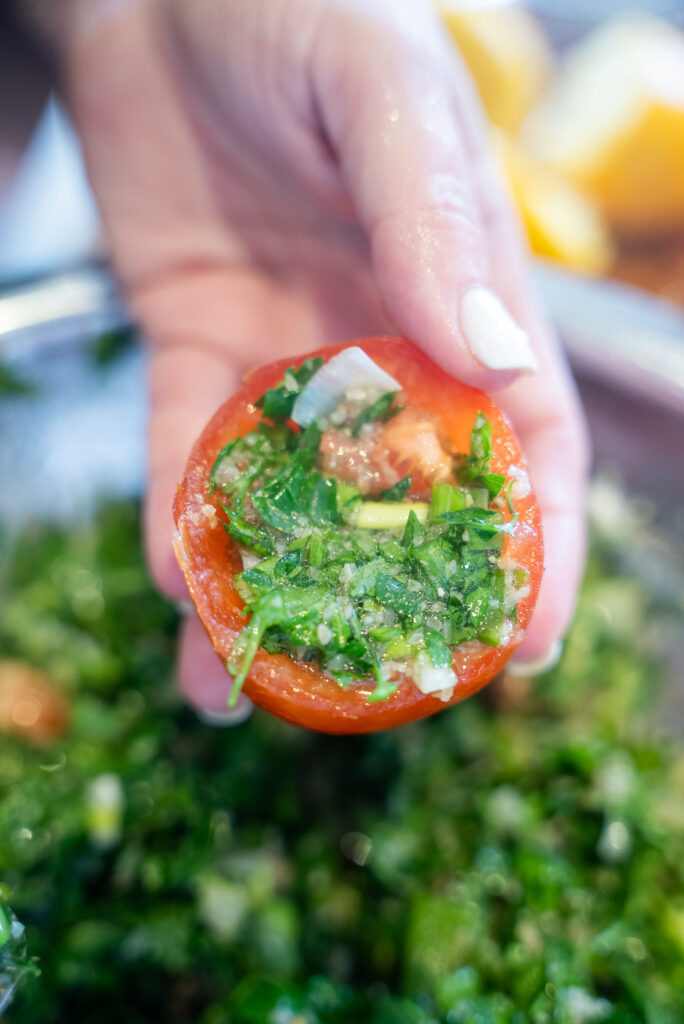 A cutting board with tomatoes, celery and herbs.