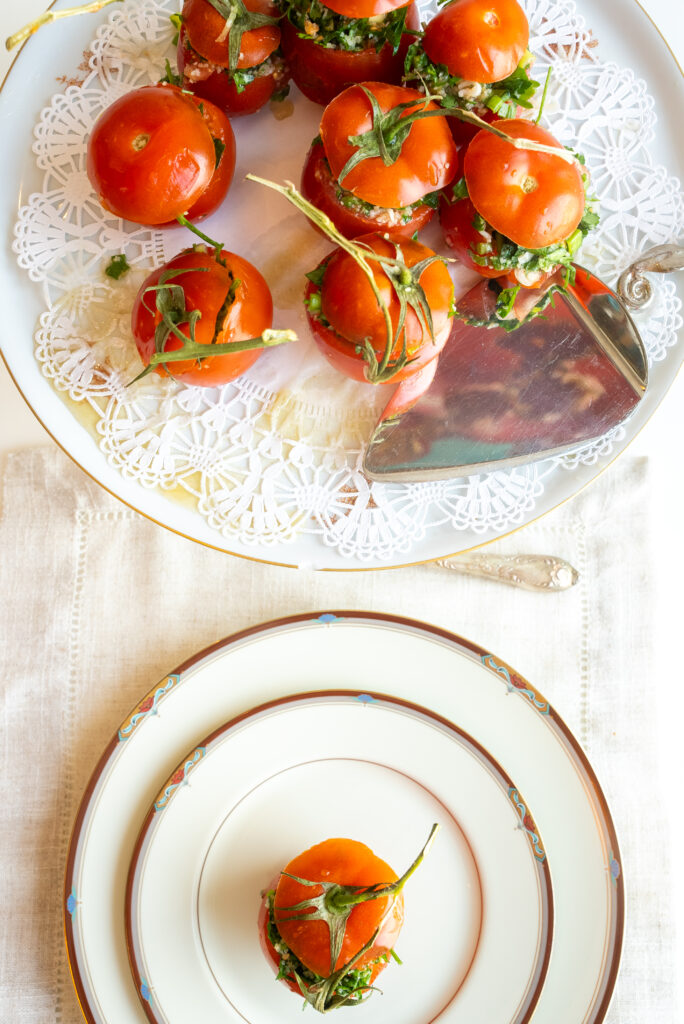 A cutting board with tomatoes, celery and herbs.