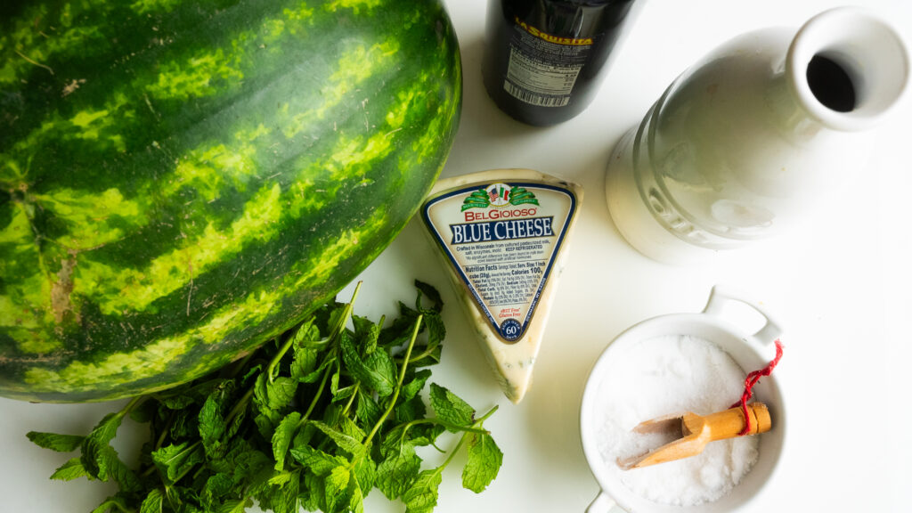 A watermelon, cheese and mint on the table.