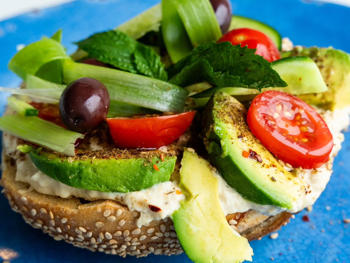 A sandwich with avocado, tomatoes and other vegetables.