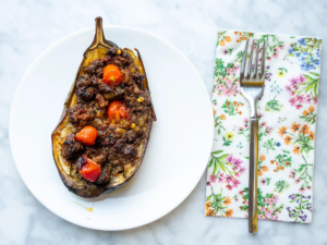 A plate with a stuffed eggplant and fork on it