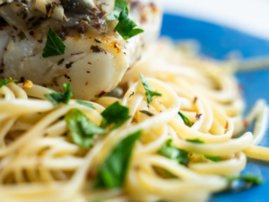 A plate of pasta with meat and parsley.