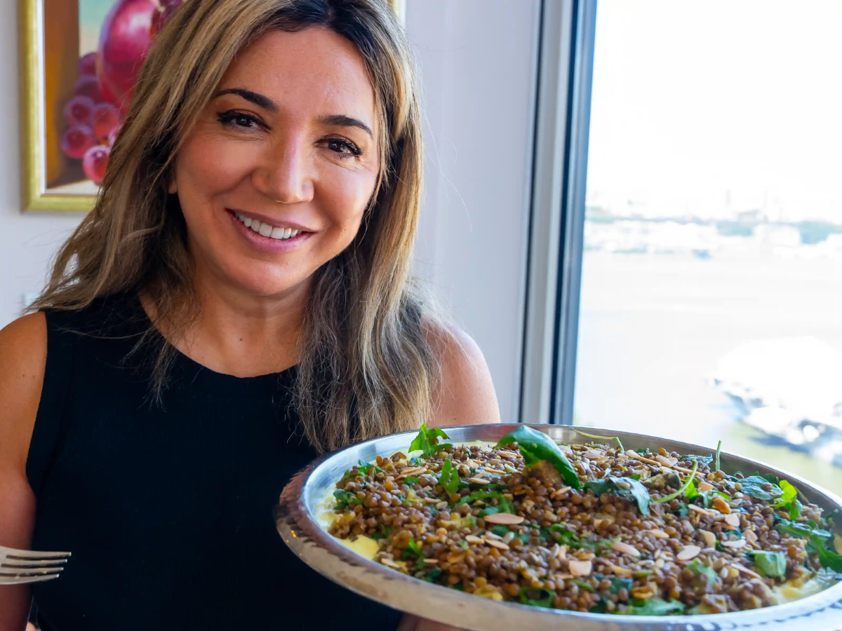 A woman holding a tray of food in front of a window.