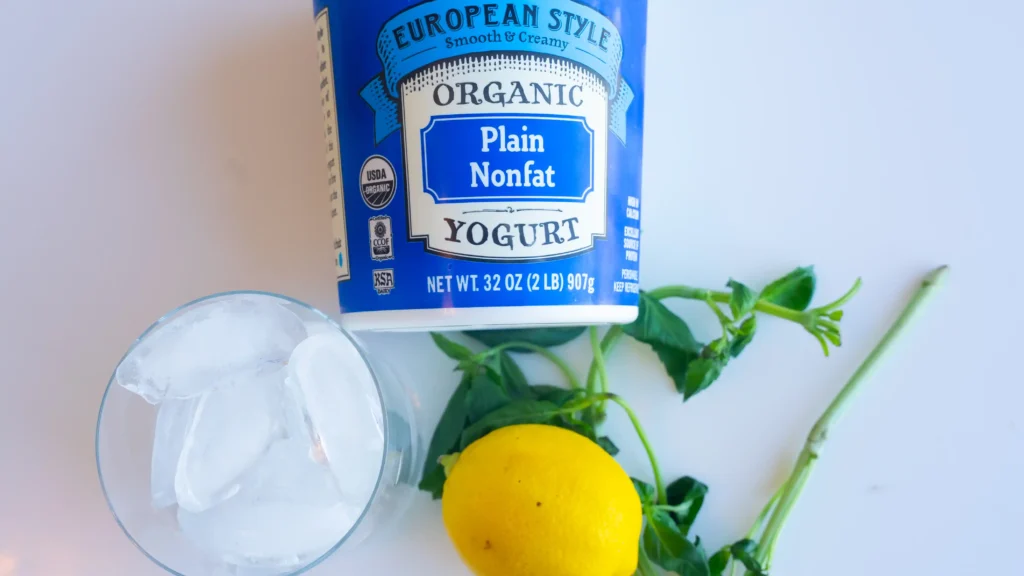 A yogurt container and lemon sitting on top of a table.